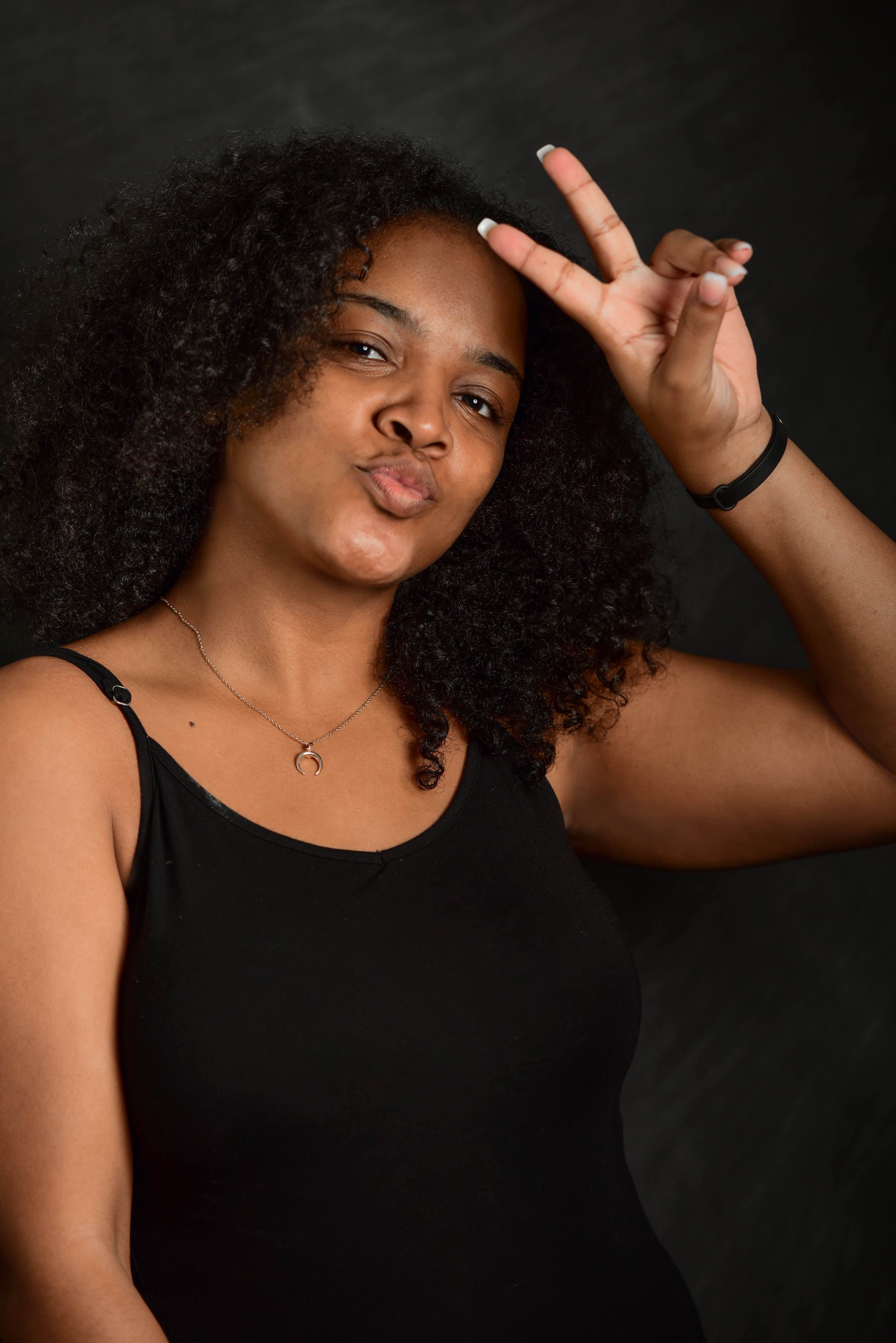 A woman wearing a black shirt making a peace sign with her hand.