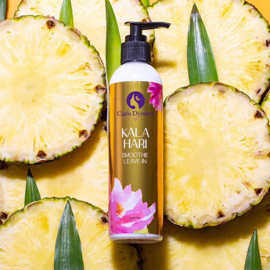 A bottle of Kala Hari Smoothe Leave-In on top of sliced pineapples.