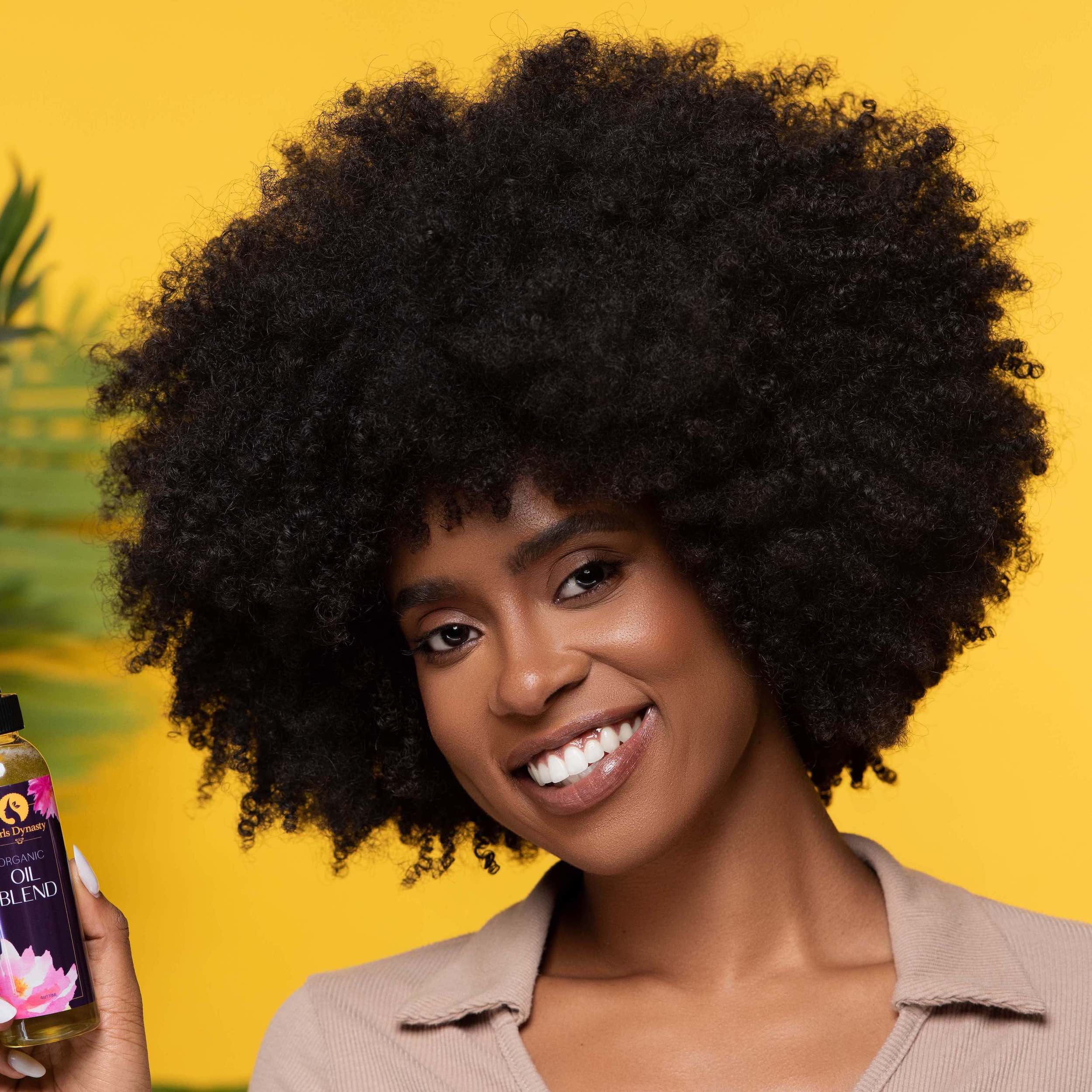 A model smiling while holding a bottle of Oil Blend in front of an orange backdrop.